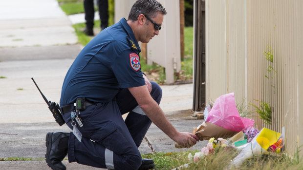 A paramedic lays flowers at the scene on Friday.