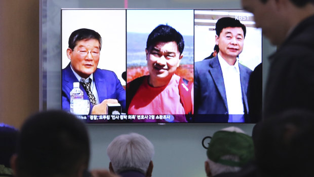 People watch a TV news report on screen displaying portraits of three Americans, from left, Kim Dong-chul, Tony Kim and Kim Hak-song, detained in North Korea.
