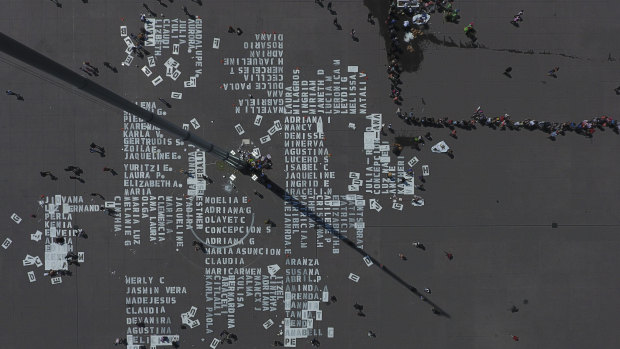 Women work on painting the names of more than 3000 victims of femicide on Mexico City's main plaza, The Zocalo, on International Women's Day.