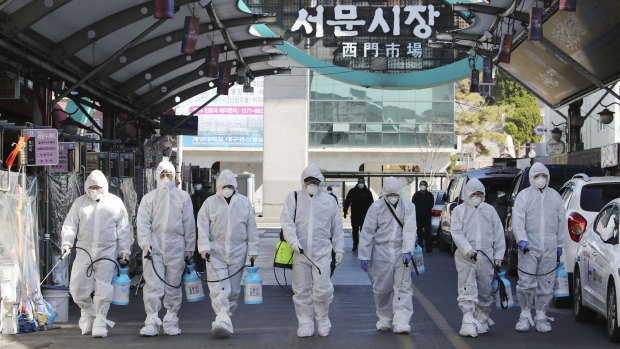 Workers spray disinfectant as a precaution against the COVID-19 at a local market in Daegu, as the country raises the alert level.