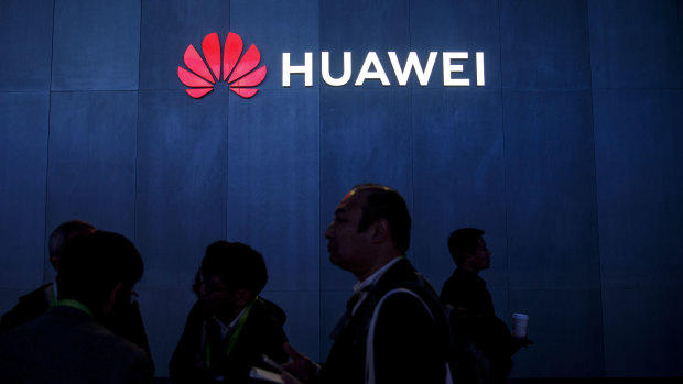Attendees walk past signage displayed outside the Huawei booth at the 2019 Consumer Electronics Show.