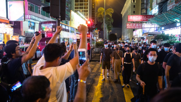 Pedestrian cheer as demonstrators march on Nathan Road during a protest in the Mong Kok district of Hong Kong, on Sunday.