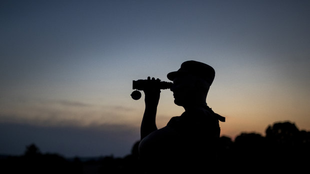 A member of the Lithuania State Border Guard Service looks through binoculars as he patrols on the border with Belarus, near the village of Purvenai, Lithuania.