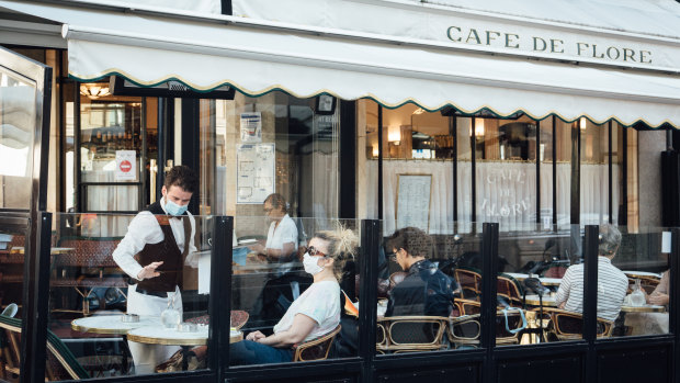 A waiter wearing a protective face mask serves a customer sat beside a protective perspex screen on a cafe terrace as it reopens for business in Paris, France. 