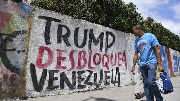 A pedestrian in Caracas passes graffiti protesting against US President Donald Trump's sanctions on Venezuela.