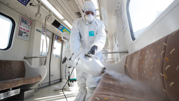 Workers wearing protective suits spray disinfectant inside a subway  in Seoul, South Korea.