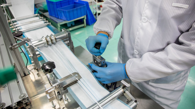 A worker operates a machine on the protective mask production line at the Mask Factory facility in Hong Kong, China.