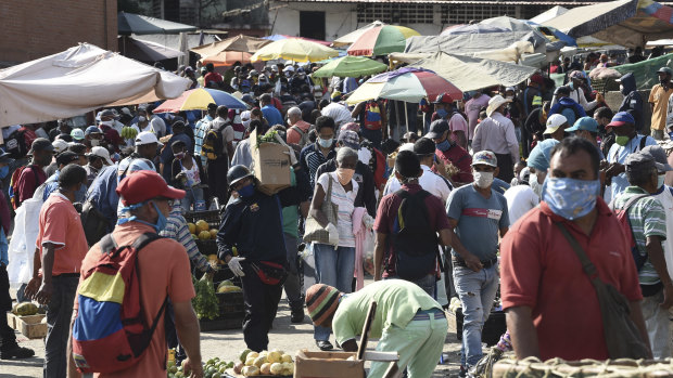 Shoppers wearing protective masks walk through the crowded Coche market in Caracas, Venezuela.