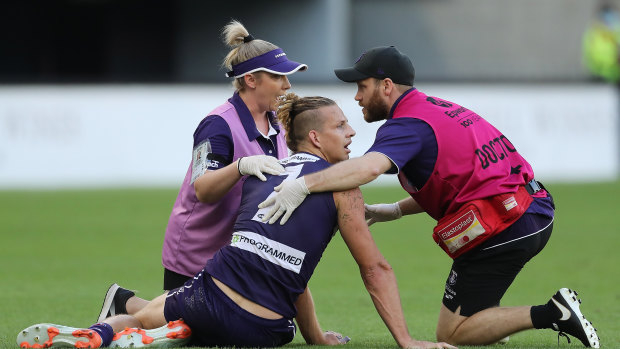 Nat Fyfe of the Dockers receives attention after a heavy knock from Sam Reid.