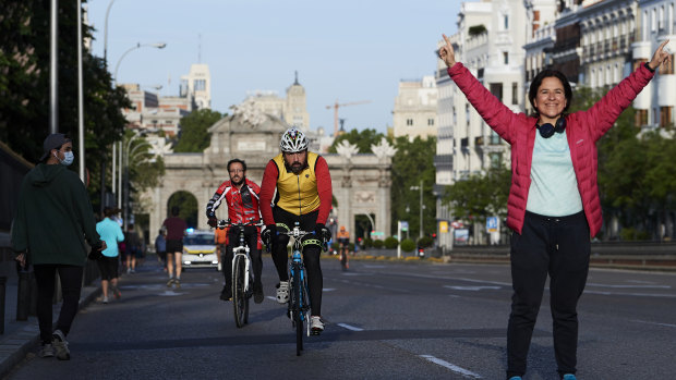 Working from home also means time to get out of the house for exercise: people running and cycling through Madrid's Puerta de Alcala.