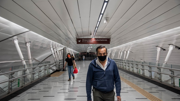 People wearing protective masks walk through the Plaza de Armas subway station in Santiago, Chile.