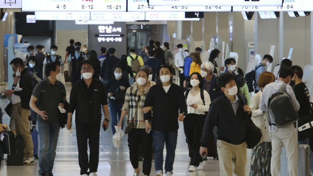 People wearing face masks arrive at the domestic flight terminal of Gimpo airport in Seoul.