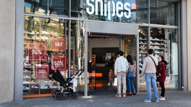 Customers form a social distancing queue to enter a Snipes footwear and sporting goods store as it reopens for business in Berlin.