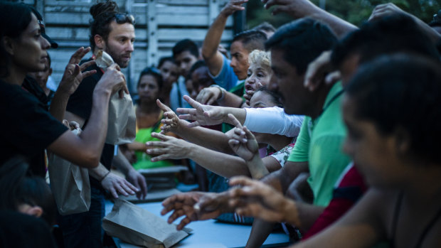 World Central Kitchen volunteers, left, distribute food in Cucuta, Colombia.