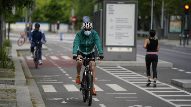 A cyclist wearing a face mask rides past a jogger in a cycle lane in Madrid, Spain.