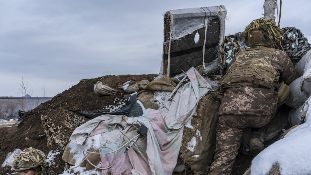 A Ukrainian soldier, uses a small hand-held periscope to view the positions of Russian-backed troops from a small bunker.