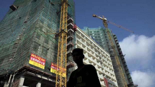 A pedestrian walks past a construction site in Sihanoukville, Cambodia as yet another Chinese-funded building goes up.