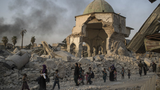 Fleeing civilians walk past the heavily damaged al-Nuri mosque as Iraqi forces continue their advance against Islamic State.