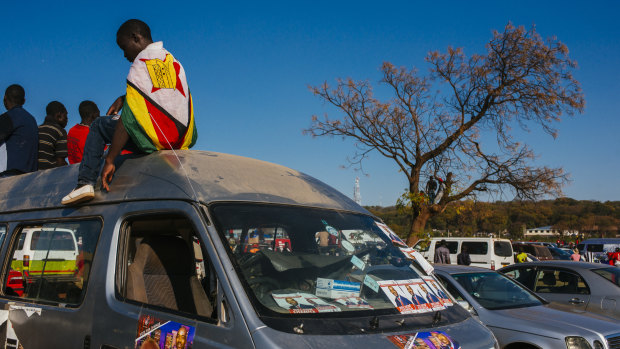 A supporter wearing a Zimbabwean national flag while sitting on top of a vehicle during a campaign rally in Harare, Zimbabwe, on Saturday.