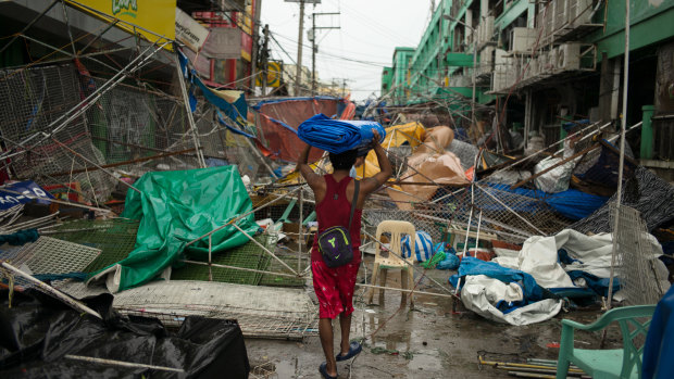 A man carries a tarp over his head as he walks through the wreckage and debris of street stalls at a bazaar after typhoon Mangkhut in Tuguegarao, Cagayan province, the Philippines, on Saturday.