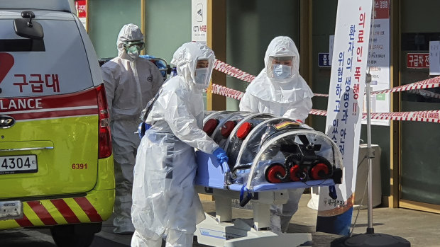 Medical workers wearing protective gear move a patient suspected of contracting coronavirus to hospital in Daegu, South Korea.
