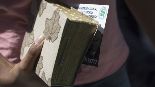 A woman holds her Bible, and an electoral leaflet promoting two candidates that was distributed at the Assembly of God Victory in Christ Church in Rio de Janeiro, Brazil.