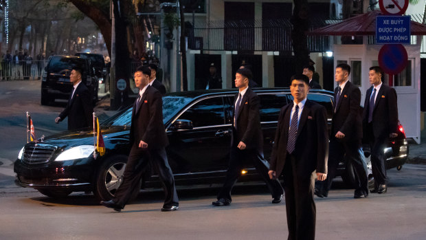 Bodyguard walk alongside a limousine carrying Kim as he arrives in Vietnam.