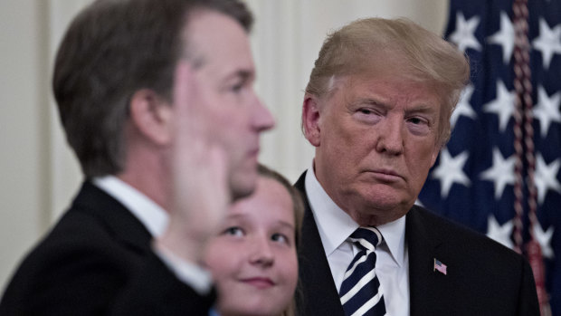 Donald Trump listens as Brett Kavanaugh takes the oath to become a judge on the US Supreme Court.