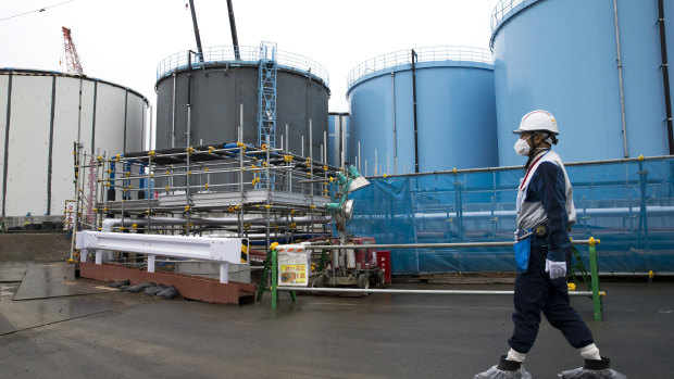 An employee walks past storage tanks for contaminated water at the tsunami-crippled Fukushima Dai-ichi nuclear power plant.