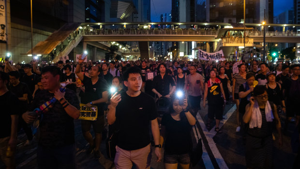 Demonstrators shine smartphone lights as the protest continues into the night.