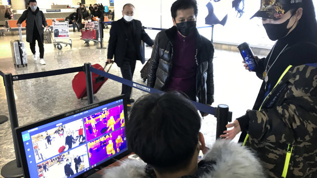 Travelers pass through a health screening checkpoint at Wuhan Tianhe International Airport.