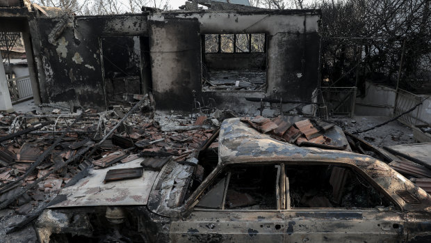 A burnt automobile stands in front of a destroyed house in Mati .