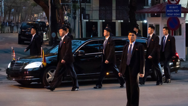 Bodyguard walk alongside a limousine carrying Kim as he arrives in Vietnam in February.