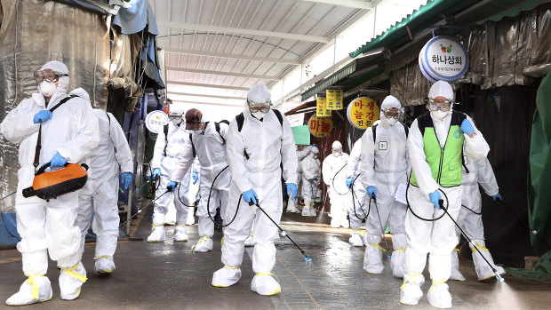 Workers wearing protective suits spray disinfectant as a precaution against the coronavirus at a market in Bupyeong, South Korea.