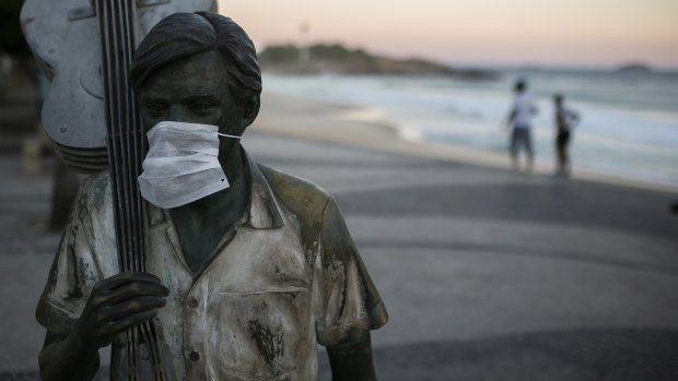 Statue of a Brazilian musician and composer Antonio Carlos 'Tom' Jobim wearing a mask on Arpoador beach on in Rio de Janeiro, Brazil. 