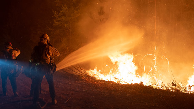 Firefighters douses flames with water during a firing operation to contain the Bear fire in Oroville, California. 