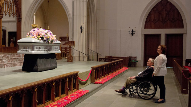 Former President George HW Bush looks at the casket of his wife.