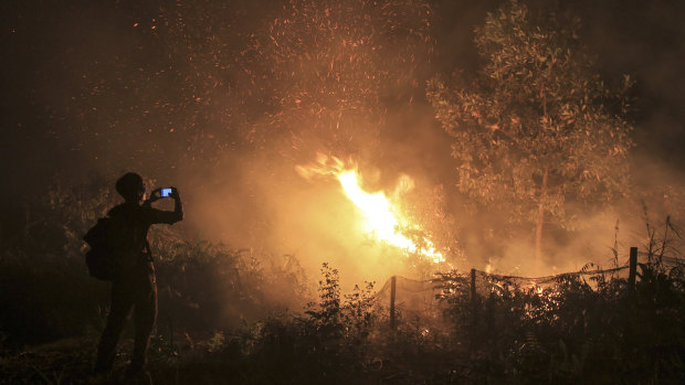 A man uses his mobile phone to take photos of a forest fire in Kampar, Riau province, Indonesia.