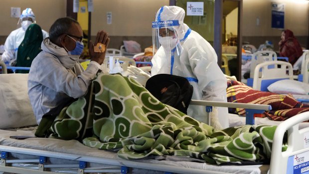 A health workers in personal protective equipment assists a patient at a makeshift COVID quarantine facility set up in a banquet hall in Delhi, India,