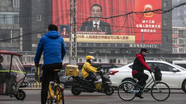 My way or the highway: Beijing commuters travel past a screen broadcasting Chinese Premier Li Keqiang speaking at the National People’s Congress. 