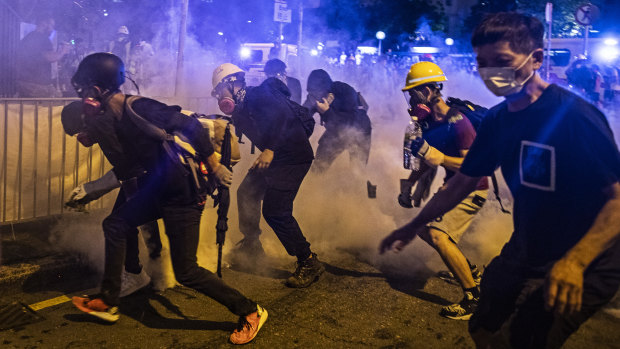 Demonstrators stand in a cloud of tear gas during a protest in the Wong Tai Sin district of Hong Kong, China.