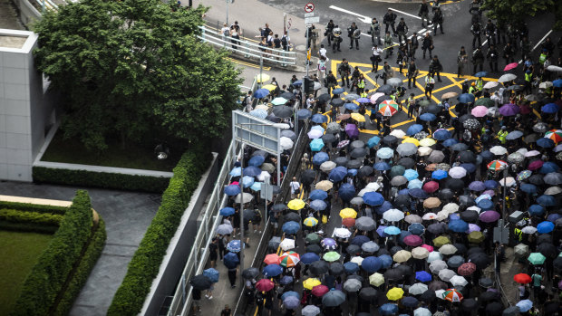 Demonstrators holding umbrellas march past riot police on Garden Road towards the Government House during a protest in the Central district of Hong Kong.