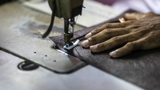 A worker uses a sewing machine while manufacturing a wallet at a leather workshop in Dharavi.