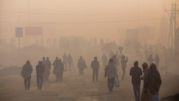 Pedestrians walk along a road shrouded in smog in Prayagraj, Uttar Pradesh, India, in January.