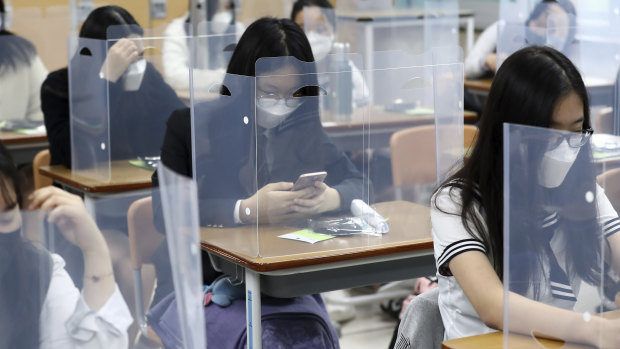 Senior students wait for class to begin with plastic boards placed on their desks at Jeonmin High School in Daejeon, South Korea.