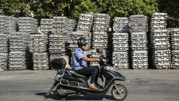 Bundles of aluminum ingots sitting stacked on the side of a road near a China National Materials Storage and Transportation Corp. stockyard.