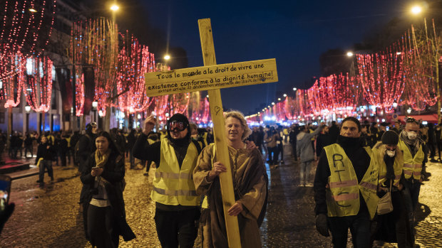 Demonstrators wearing yellow vests hold a cross with an article of the declaration of human rights during a demonstration on the Champs-Elysees in Paris on Saturday.