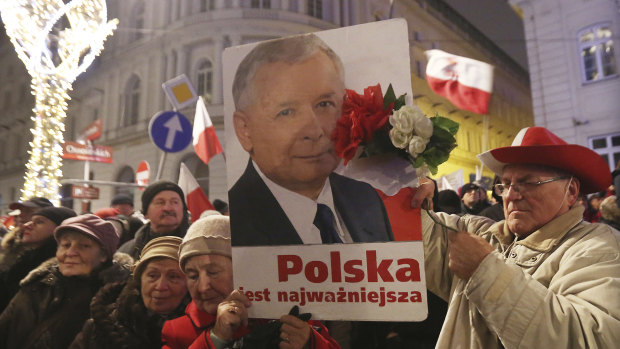 Supporters of the ruling Law and Justice party hold a portrait of the leader Jaroslaw Kaczynski as they attend a pro-government rally in front of the presidential palace, in Warsaw, Poland in 2016.