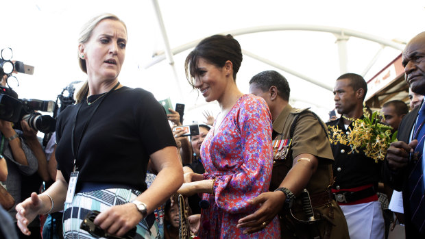 Meghan, Duchess of Sussex is escorted through a market in Suva, Fiji, by her bodyguard in October.
