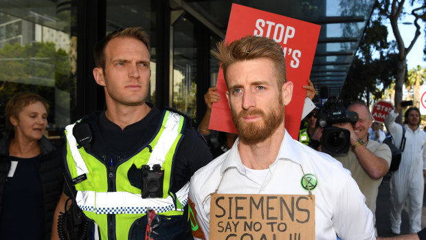 Police arrest a protester who glued his hand to a window during a protest at Siemens. 